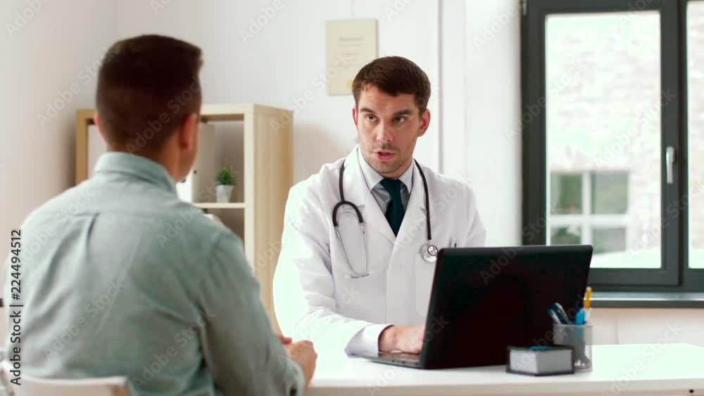 medicine, healthcare and technology concept - doctor with laptop computer and male patient talking at hospital