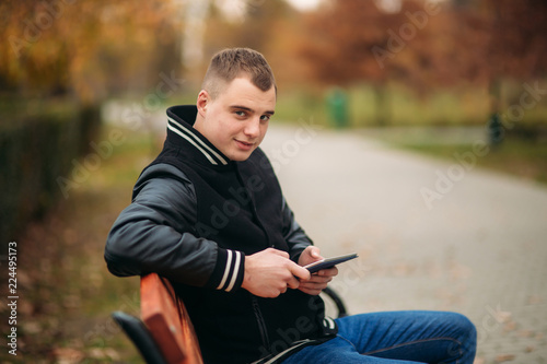 A young guy in a black jacket uses a tablet