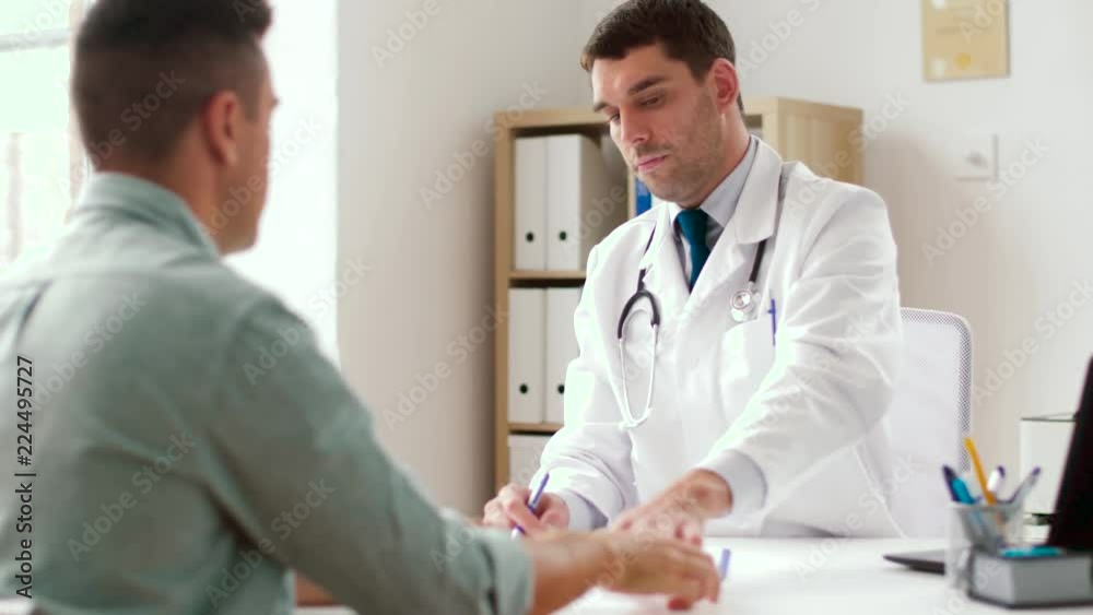 medicine, healthcare and people concept - doctor giving prescription for male patient at clinic