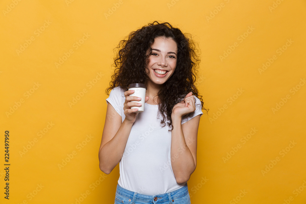 Happy cute young woman posing isolated over yellow background holding cup of coffee. Happy cute young woman posing isolated over yellow background holding cup of coffee.