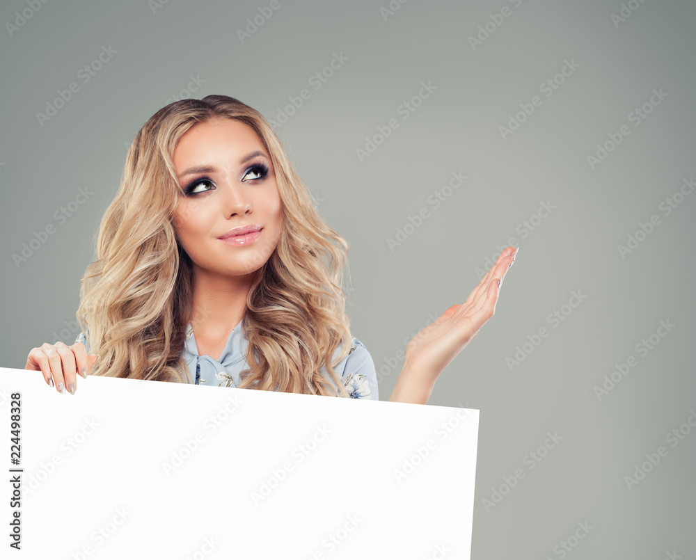 Naklejka premium Smiling woman holding white blank paper banner background and looking up