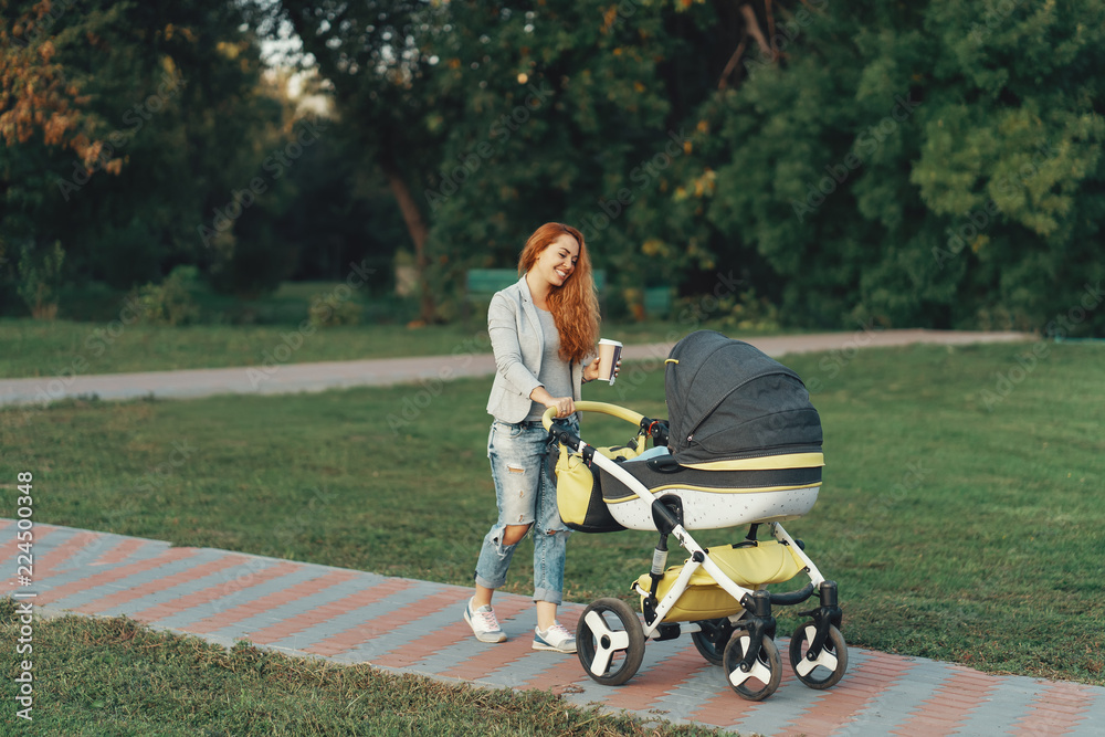 Young mother walking with her child in the morning while drinkin Young mother walking with her child in the morning while drinkin