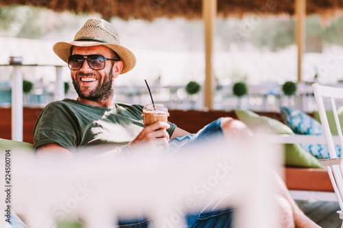 Young man drinking ice coffee in a beach bar