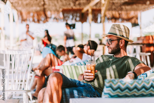 Young man drinking ice coffee in a beach bar photo