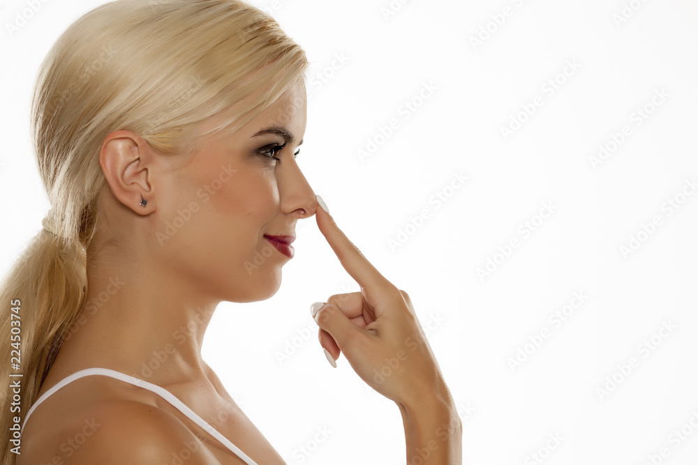 profile of young blonde woman with long hair touching her nose on white background profile of young blonde woman with long hair touching her nose on white background