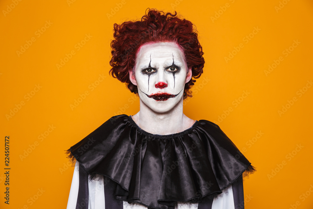 Sad clown man 20s wearing black costume and halloween makeup looking at ...