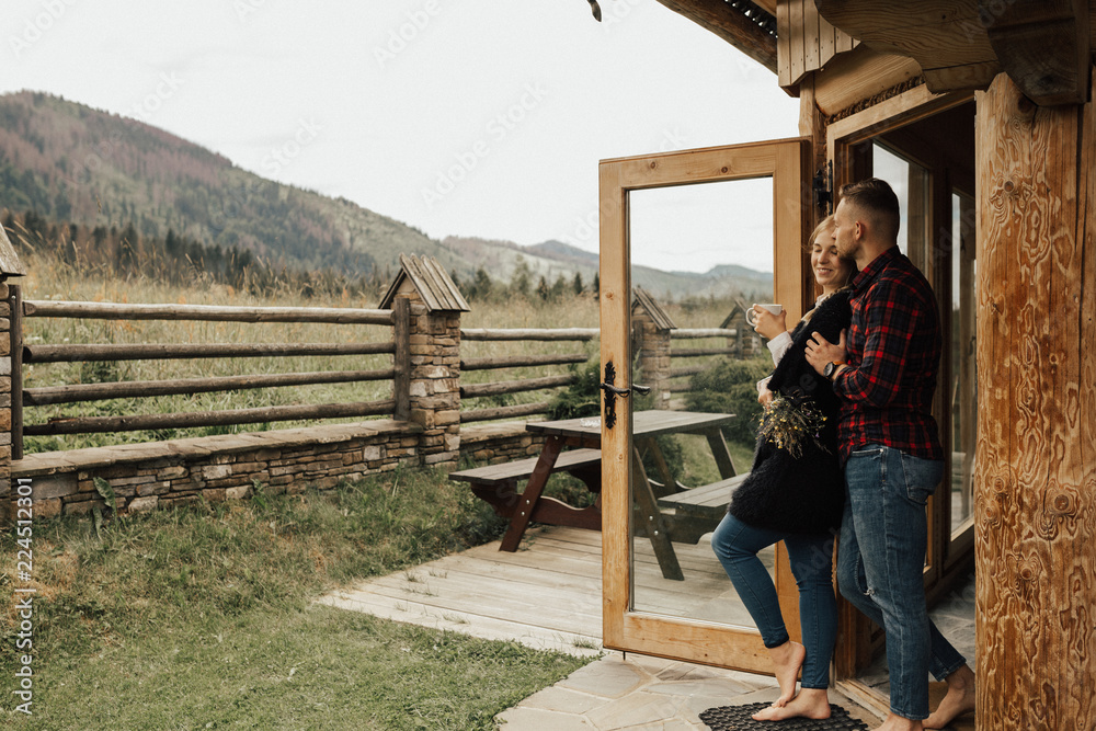 Couple drinking morning coffee and kising in the wooden mountain's house
