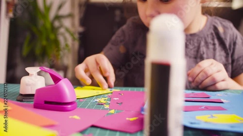 Crane shot. Scrapbooking. Little girl glueing colored paper. Children's creativity, handicraft