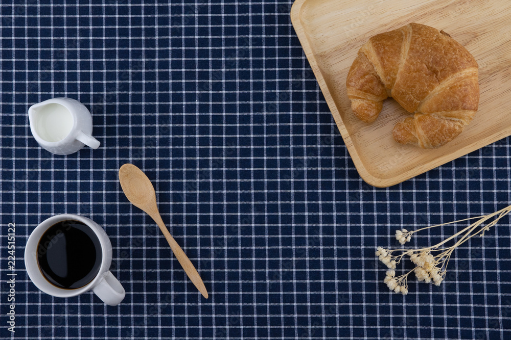 Φωτογραφία A cup of coffee, milk and croissant with white flower and wooden spoon on dark b