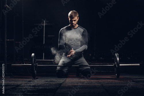 Man is preparing to press bar, weightlifting. Hand in talc. Sport workout background.