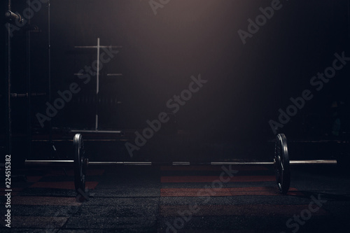 Obraz na plátně Bar for weight lifting on dark background in gym barbell.