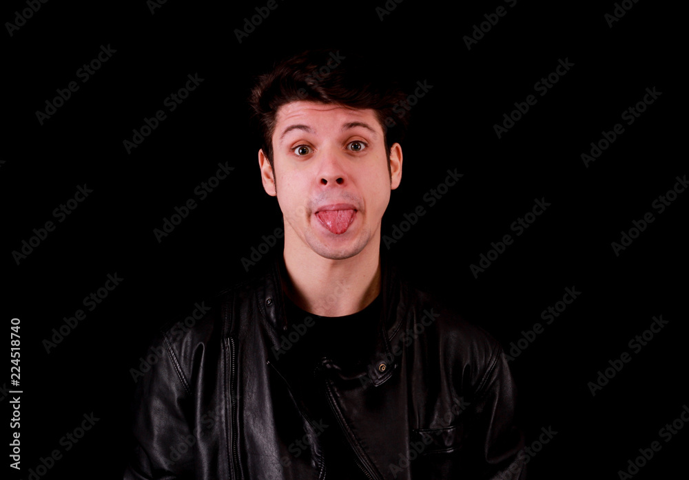 Muscular handsome young man pulling his tongue out with black tee shirt in front of black background