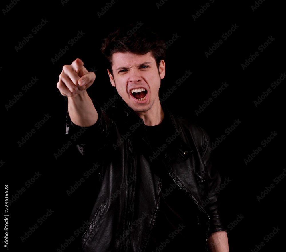 Muscular handsome young angry man pointing out with black jacket in front of black background Muscular handsome young angry man pointing out with black jacket in front of black background