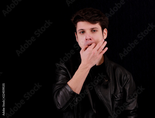 Muscular handsome young man whistling with black jacket in front of black background
