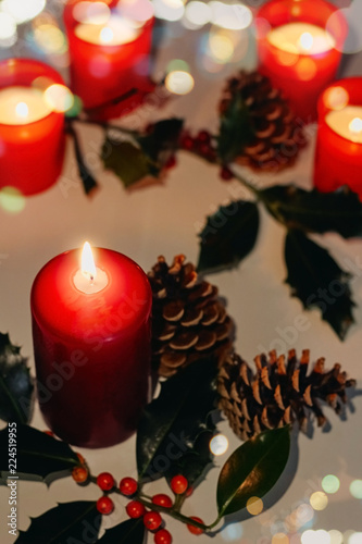 Christmas and New Year composition. Lit candles  fir cones and branch of holly
