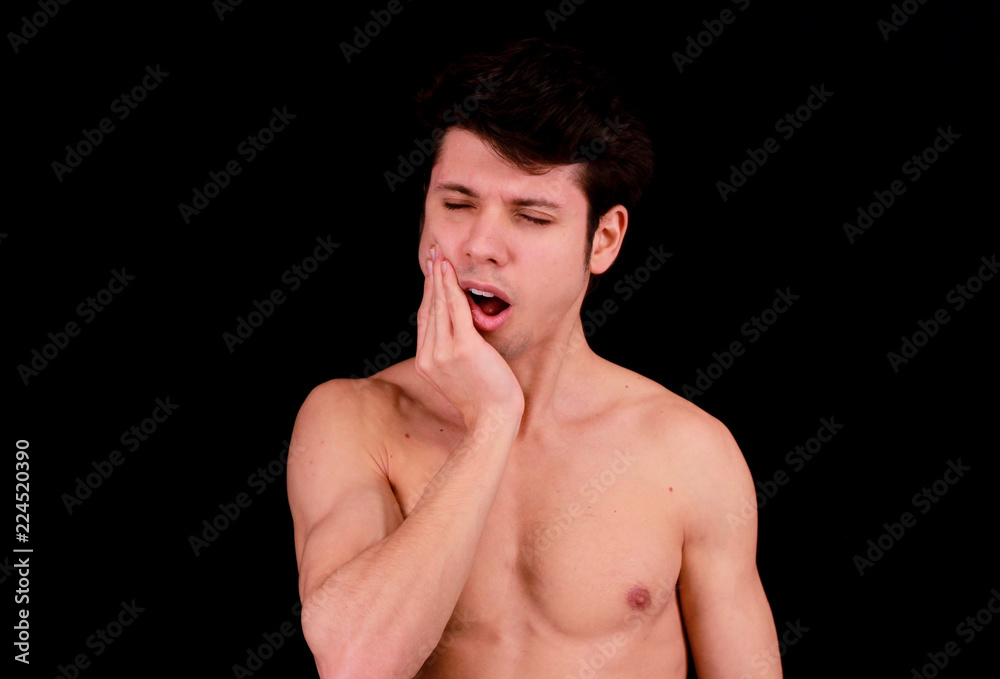 Muscular handsome young man having tootache in front of black background Muscular handsome young man having tootache in front of black background