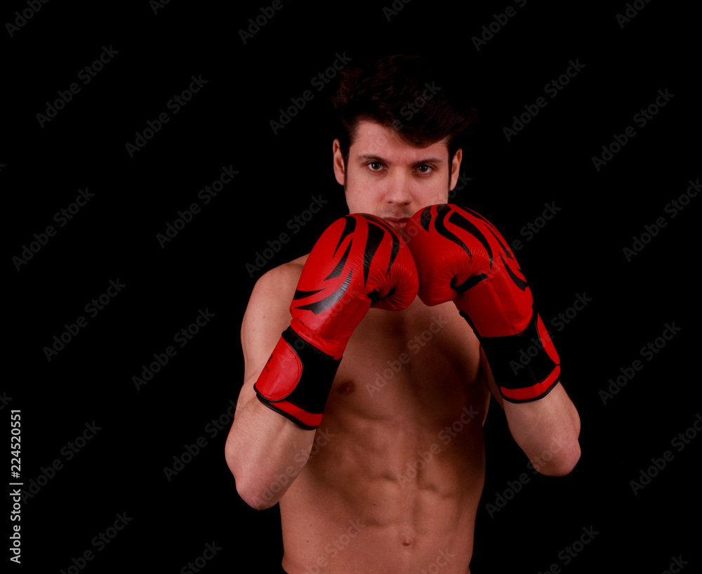 Muscular handsome young man with box gloves in front of black background