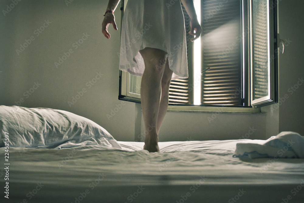 Gambe di donna vestita di bianco su letto bianco Stock Photo