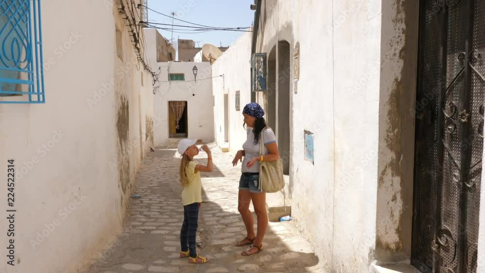 Tourist girl drinking water from bottle on narrow street while walk at old city Tourist girl drinking water from bottle on narrow street while walk at old city