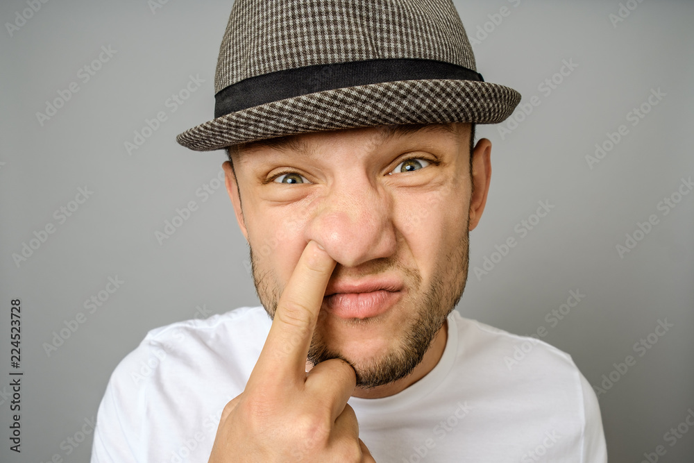 Man picking his nose on gray background Man picking his nose on gray background