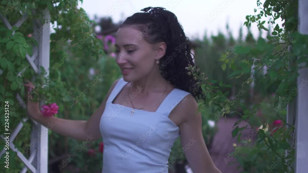 Adult lady with flower walks in the garden Adult lady with flower walks in the garden