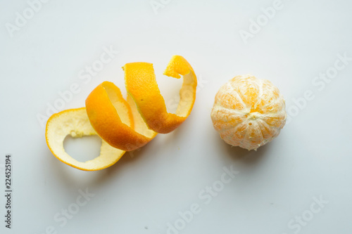 diet vegan: a whole ripe peeled tangerine on the table next to figuratively cut zest photo