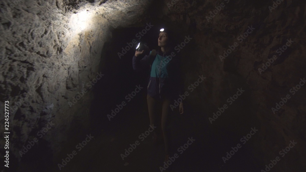 Obraz premium portrait of a girl, the tourist, the researcher goes into the cave with a flashlight