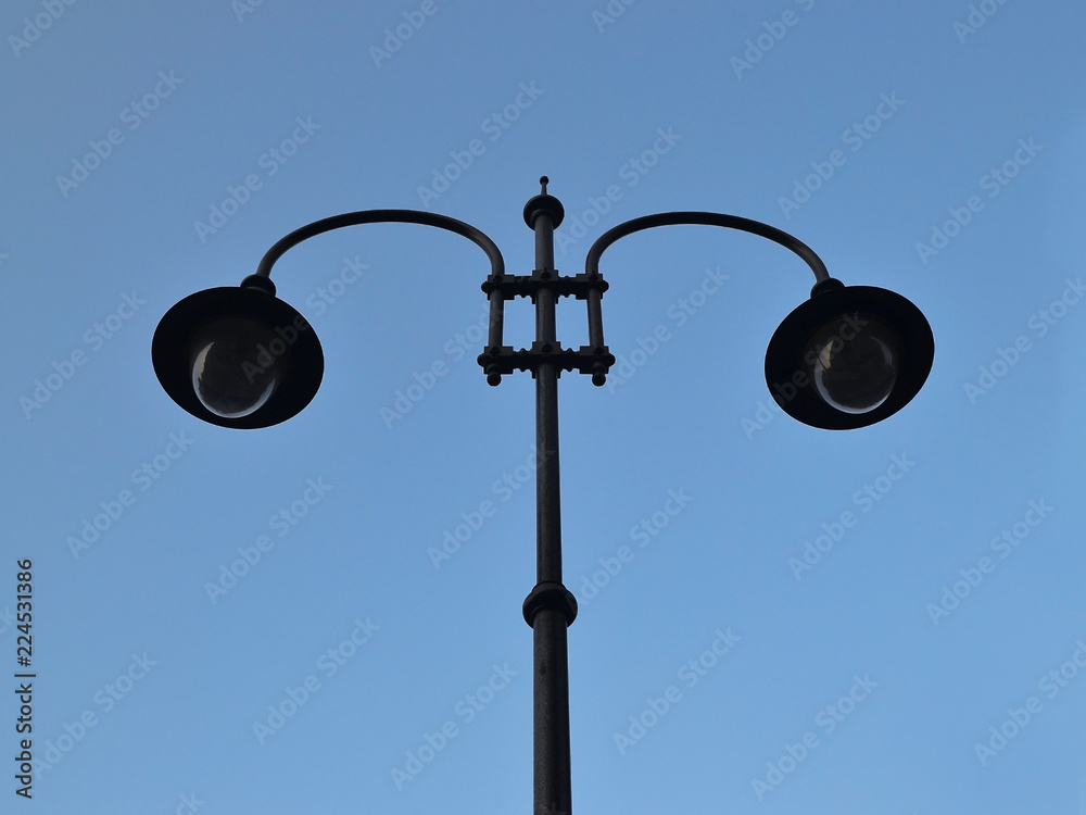 A street lamp with two lights against a blue sky, bottom view A street lamp with two lights against a blue sky, bottom view