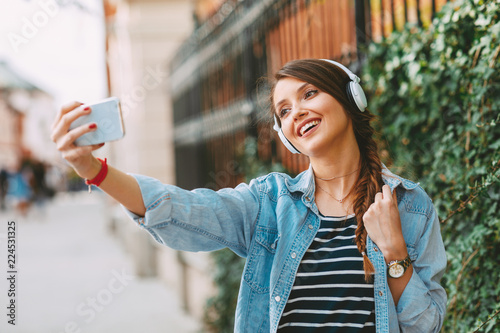 Young woman listens to music via headphones and smartphone in the city