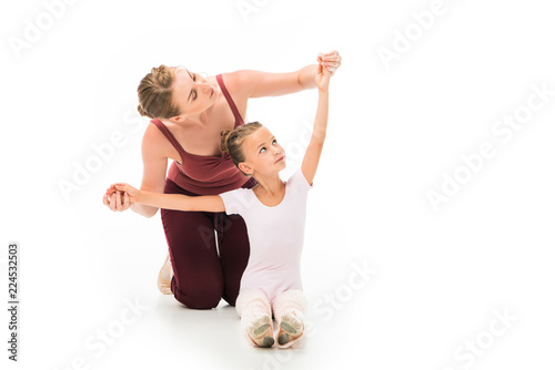 adult female trainer helping little kid exercising isolated on white background
