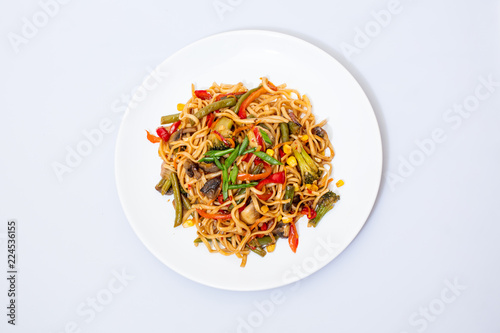 Wok food on a white ceramic plate is tasty and fresh with sauce on a light isolated background