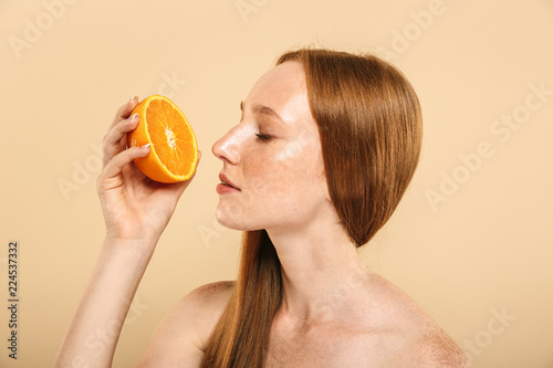 Redhead woman holding orange.