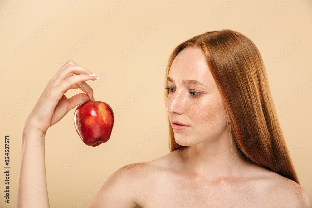 Pretty young redhead woman holding apple looking aside. Pretty young redhead woman holding apple looking aside.