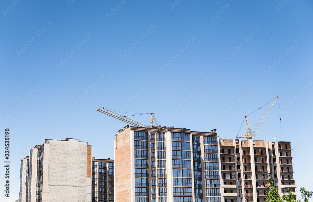 Construction of a high-rise building with a crane. Building construction using formwork. Cranes and buildings against the blue sky.