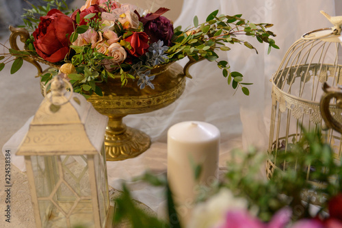 colorful wedding bouquets in gold vase on the Desk, near the white candle and decorations