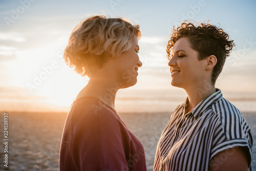 Young lesbian couple enjoying a romantic beach sunset together
