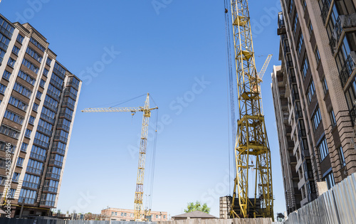 Construction of a high-rise building with a crane. Building construction using formwork. Cranes and buildings against the blue sky.
