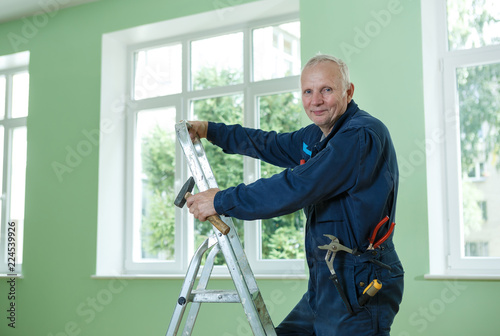 middle-aged senior man worker is working indoors fixing fitting screwing repairing