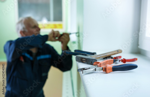 middle-aged senior man worker is working indoors fixing fitting screwing repairing