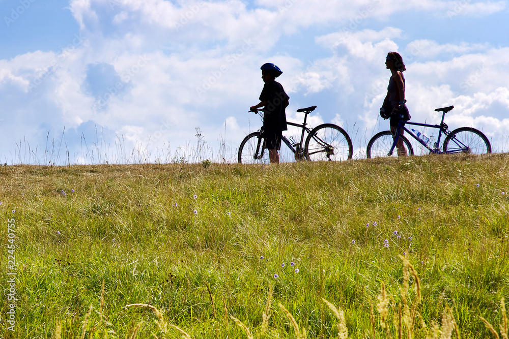 Fototapeta premium unidentifiable bikers on the meadow, Czech republic - silhouette of people with bicycles in the nature