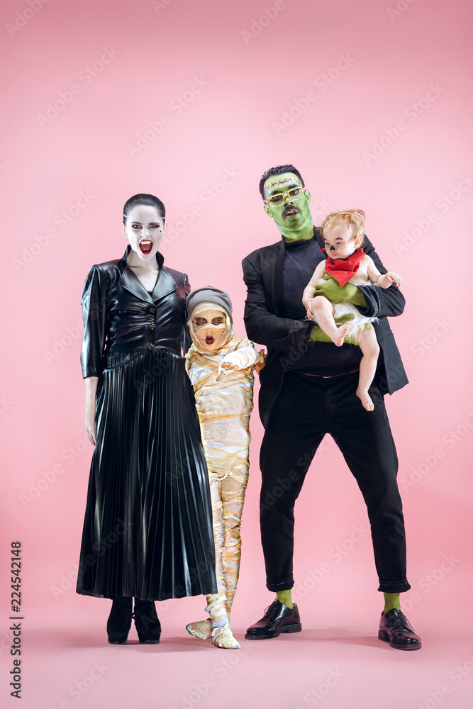 Halloween Family. Happy Father, Mother and Children Girls in Halloween Costume and Makeup. Bloody theme: the crazy maniak faces on pink studio background