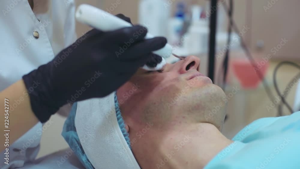 Men`s cosmetology. Young male receiving facial procedures at beauty clinic. Peeling skin Men`s cosmetology. Young male receiving facial procedures at beauty clinic. Peeling skin
