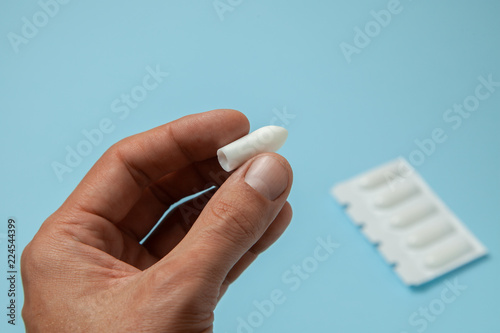 Suppository for anal or vaginal use in the hands of a man. Candles for treatment of hemorrhoids, temperature, thrush, inflammation