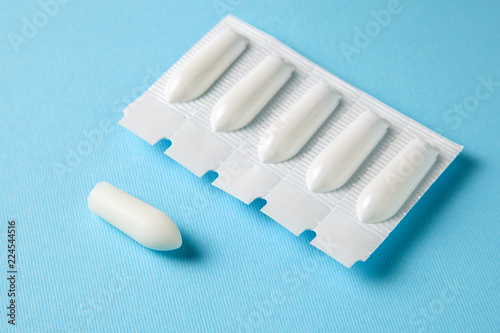 Suppository for anal or vaginal use on a blue background. Candles for treatment of hemorrhoids, temperature, thrush, inflammation