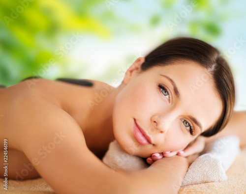 wellness  spa and beauty concept - close up of beautiful woman having hot stone therapy over green natural background