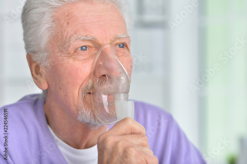 Portrait of senior man with inhaler at home