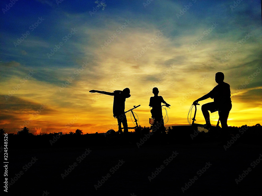 Silhouette of boys with bike in beautiful light.
