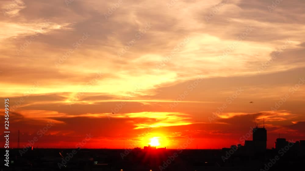  4K orange sunset as the massive sun sets into the horizon above the city