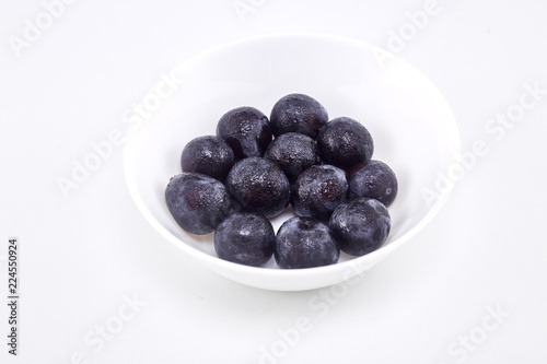 Black grape in bowl on white
