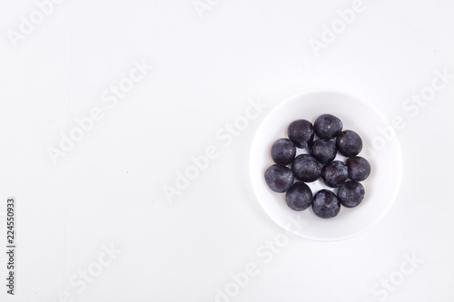 Black grape in bowl on white